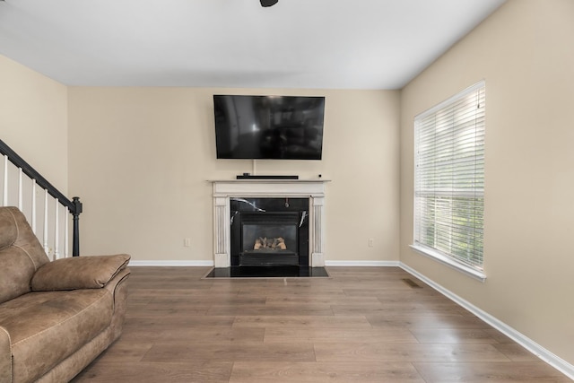 living room with baseboards, a high end fireplace, wood finished floors, and stairs