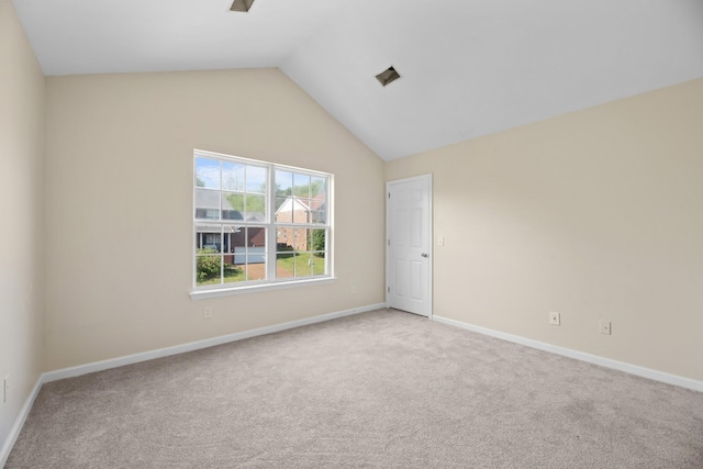 spare room featuring carpet floors, vaulted ceiling, and baseboards