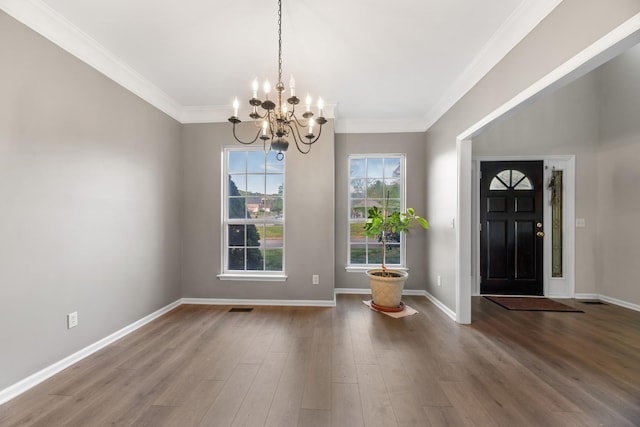 entrance foyer featuring crown molding, wood finished floors, baseboards, a notable chandelier, and visible vents