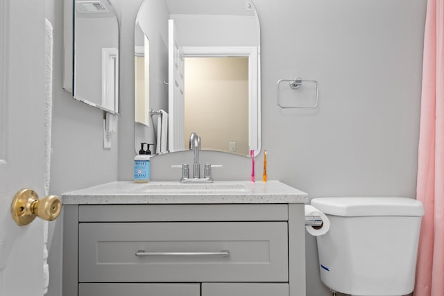 bathroom featuring toilet, vanity, and visible vents