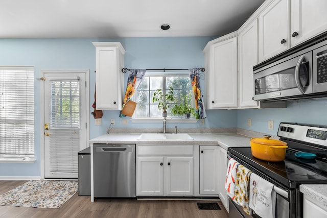 kitchen featuring light countertops, appliances with stainless steel finishes, white cabinetry, and a sink