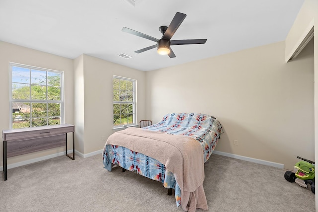 carpeted bedroom with a ceiling fan, baseboards, and multiple windows