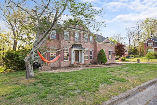 colonial inspired home with a front lawn, brick siding, and central air condition unit