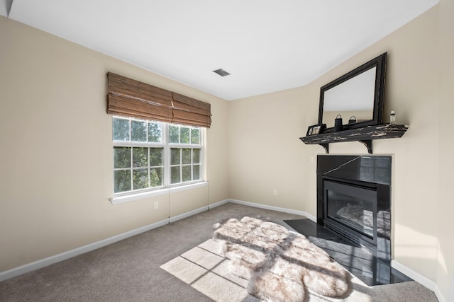 unfurnished living room featuring a fireplace with flush hearth, carpet floors, and baseboards