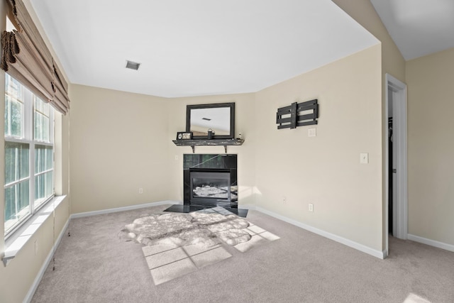 unfurnished living room with a tiled fireplace, visible vents, baseboards, and carpet