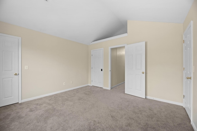 unfurnished bedroom featuring lofted ceiling, carpet flooring, and baseboards