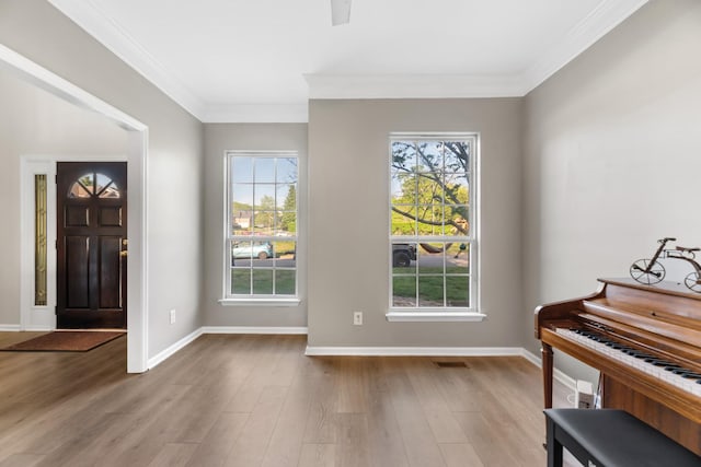 foyer featuring baseboards, wood finished floors, visible vents, and ornamental molding