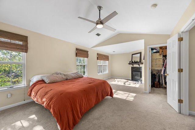 bedroom featuring lofted ceiling, a spacious closet, light colored carpet, and multiple windows