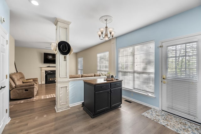 kitchen featuring open floor plan, a glass covered fireplace, a chandelier, and visible vents