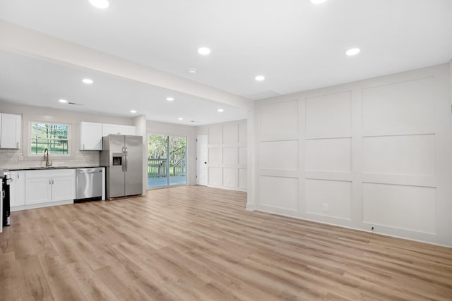 unfurnished living room with a decorative wall, light wood finished floors, and a wealth of natural light