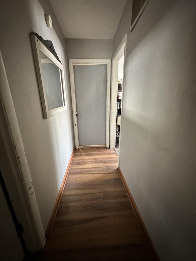 hall featuring visible vents, baseboards, and wood finished floors