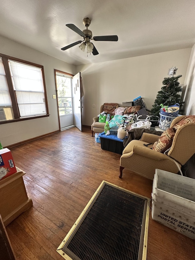 living room with baseboards, hardwood / wood-style flooring, and ceiling fan