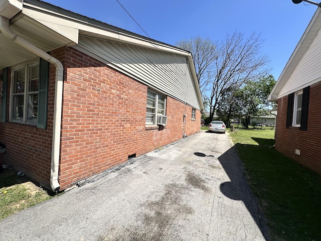view of property exterior with crawl space, a lawn, aphalt driveway, cooling unit, and brick siding