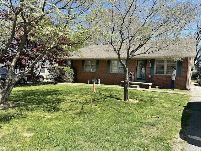 ranch-style home featuring brick siding, roof with shingles, and a front yard