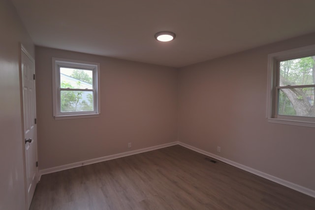 empty room with dark wood-style floors, baseboards, and plenty of natural light