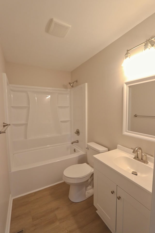 bathroom featuring visible vents, shower / bathtub combination, toilet, wood finished floors, and vanity