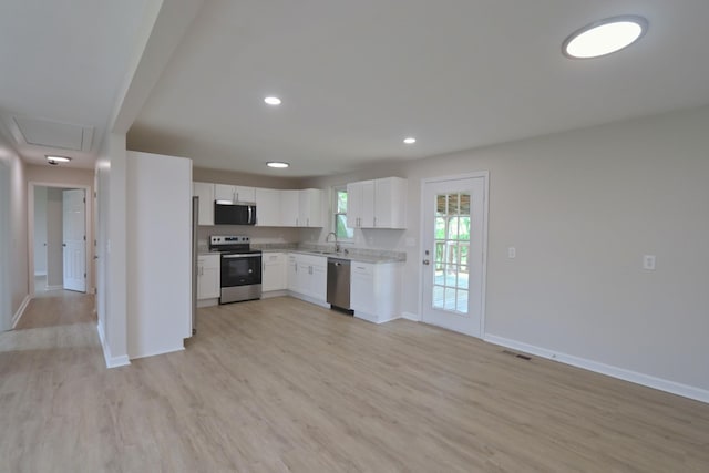 kitchen featuring appliances with stainless steel finishes, baseboards, light wood finished floors, and a sink