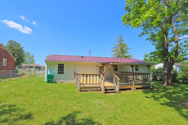 back of house with metal roof, a deck, a yard, and fence