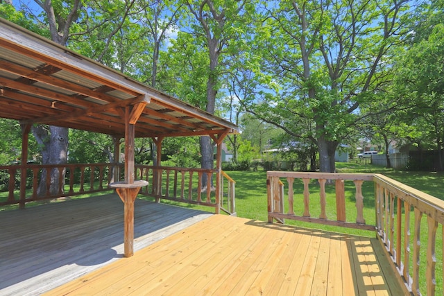 wooden terrace featuring a lawn and fence