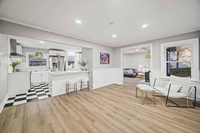sitting room with recessed lighting, light wood finished floors, crown molding, and a wainscoted wall