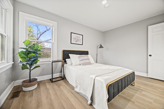 bedroom featuring light wood-type flooring, visible vents, and baseboards