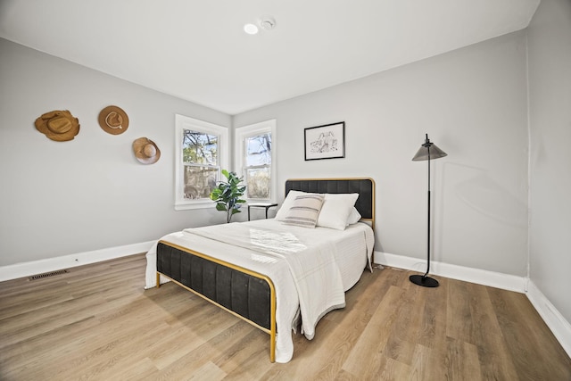 bedroom featuring baseboards, wood finished floors, and visible vents