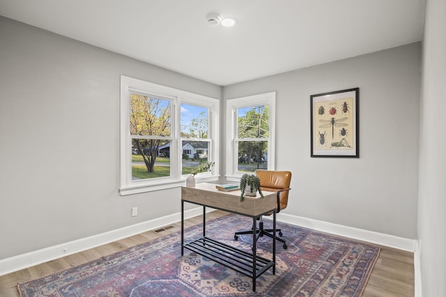 office area featuring wood finished floors, visible vents, and baseboards
