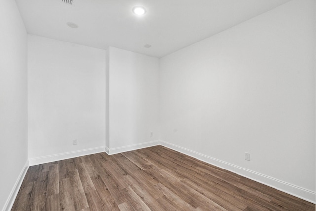 empty room featuring baseboards, recessed lighting, and dark wood-type flooring