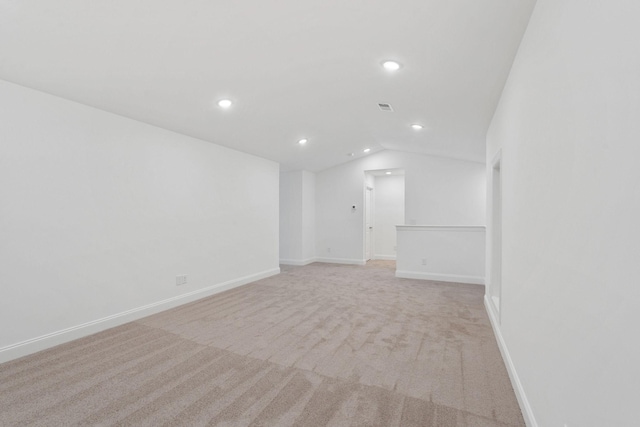 empty room with light carpet, vaulted ceiling, visible vents, baseboards, and recessed lighting