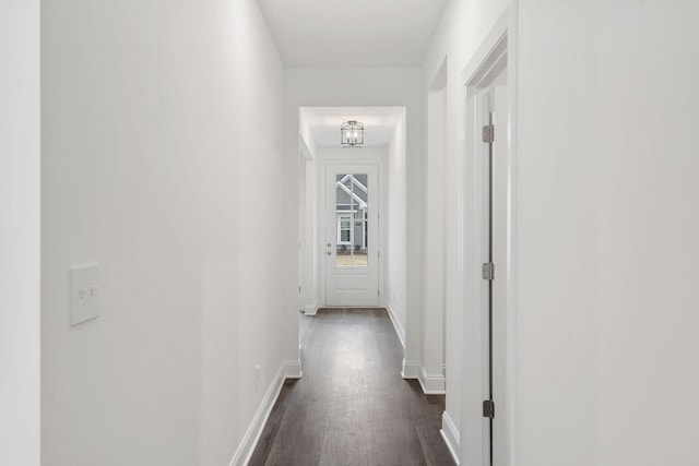 hallway with dark wood finished floors and baseboards