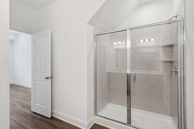 bathroom featuring baseboards, wood finished floors, and a shower stall