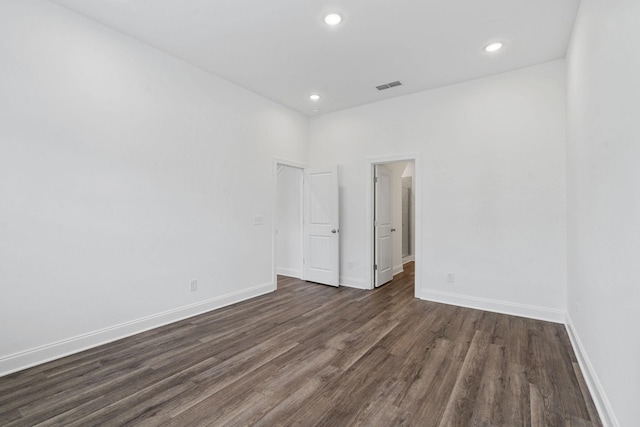 empty room featuring baseboards, dark wood-type flooring, visible vents, and recessed lighting