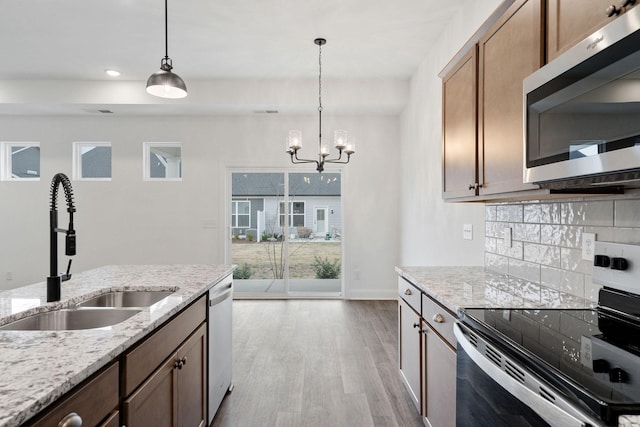 kitchen featuring a sink, a notable chandelier, wood finished floors, appliances with stainless steel finishes, and hanging light fixtures