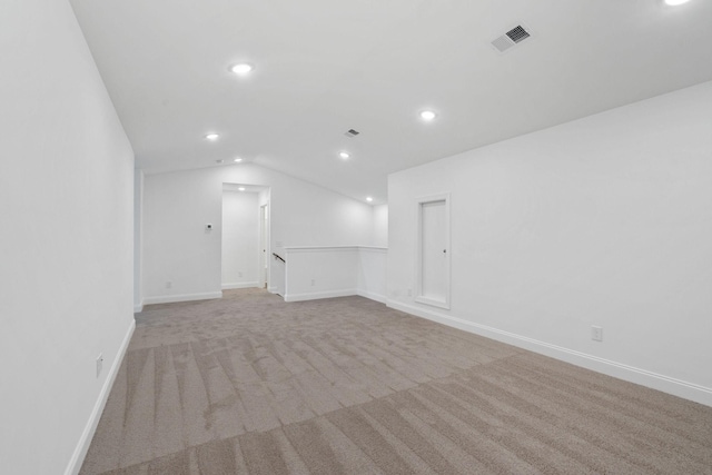 spare room featuring recessed lighting, vaulted ceiling, visible vents, baseboards, and light colored carpet