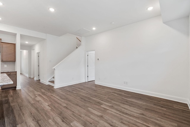 unfurnished living room with recessed lighting, baseboards, stairs, and dark wood-style flooring