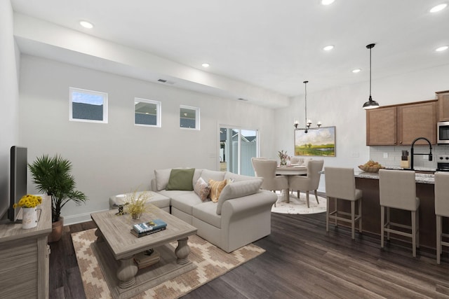 living room with recessed lighting, dark wood-type flooring, and an inviting chandelier