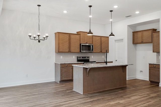 kitchen with stainless steel appliances, visible vents, decorative backsplash, and brown cabinets