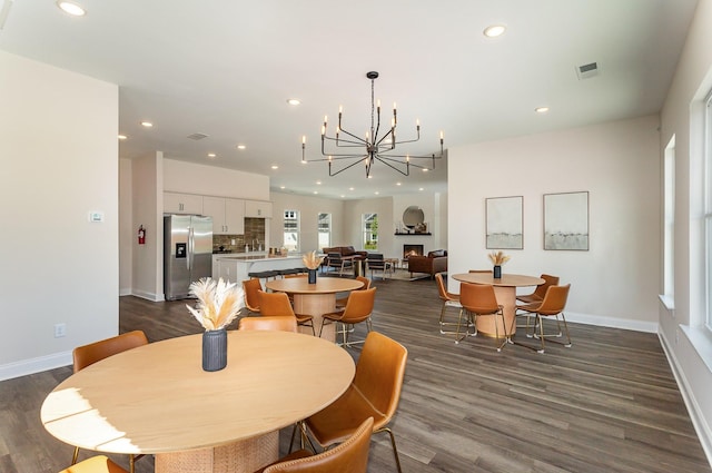 dining area with a notable chandelier, baseboards, visible vents, and dark wood-type flooring