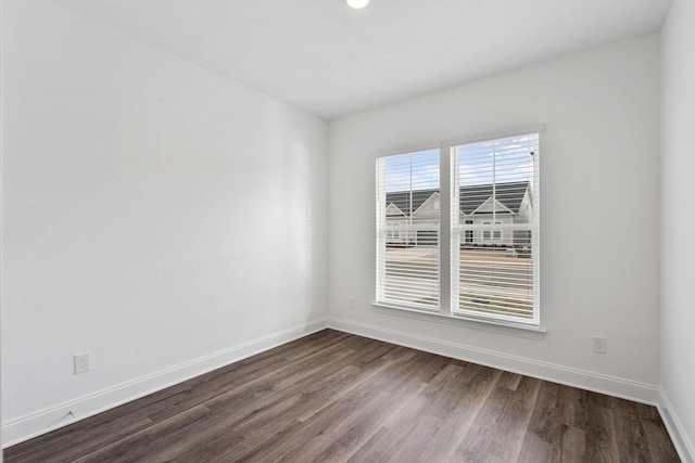 empty room featuring baseboards and dark wood-type flooring