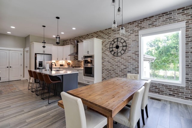 dining area with brick wall, visible vents, recessed lighting, and light wood-style floors