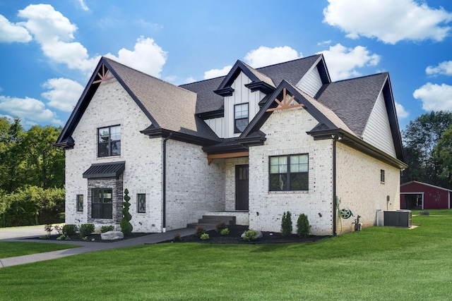 french provincial home featuring roof with shingles, a front lawn, central AC unit, brick siding, and board and batten siding