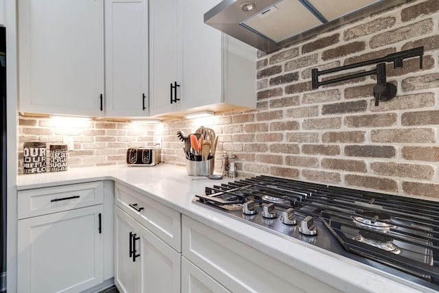 kitchen featuring white cabinets, tasteful backsplash, stainless steel gas stovetop, and exhaust hood