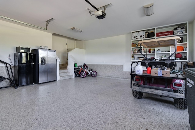 garage with stainless steel fridge with ice dispenser, a garage door opener, and freestanding refrigerator
