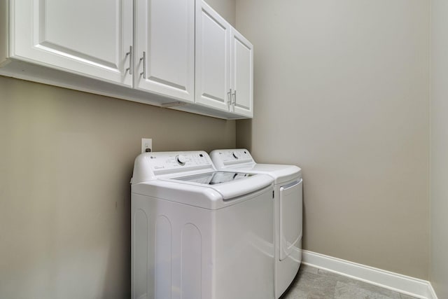 washroom with cabinet space, baseboards, washer and dryer, and light tile patterned floors