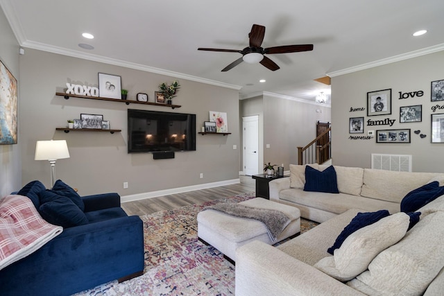 living room featuring visible vents, wood finished floors, stairway, ceiling fan, and ornamental molding