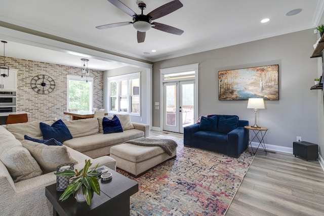 living area featuring baseboards, a ceiling fan, light wood-style floors, and plenty of natural light