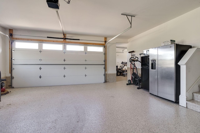 garage featuring freestanding refrigerator and a garage door opener