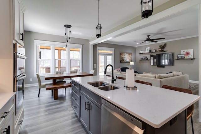 kitchen with dishwasher, baseboards, a sink, and light wood finished floors