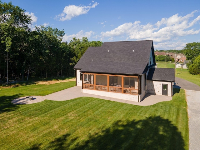 back of property featuring a patio area, a lawn, a sunroom, and roof with shingles