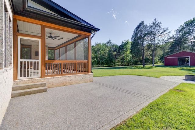 view of patio / terrace featuring an outdoor structure, a ceiling fan, and a sunroom